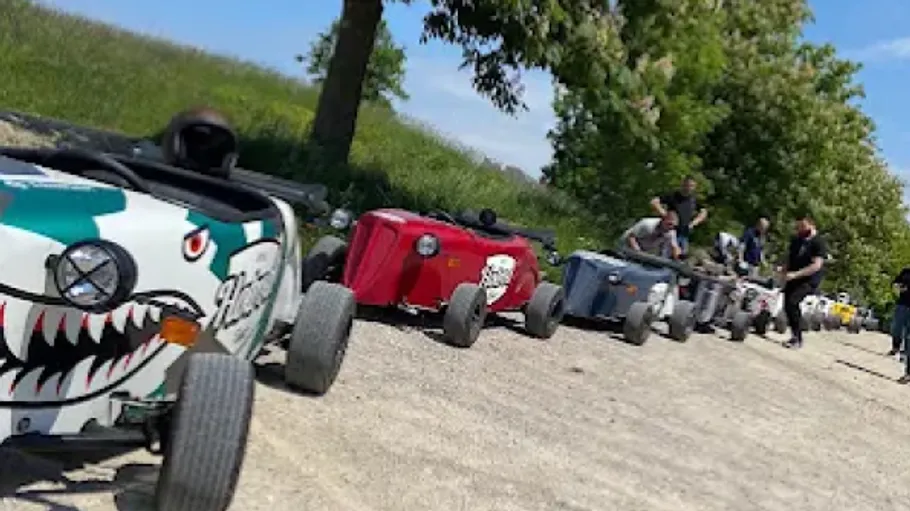Mini race cars lined up on dirt track.