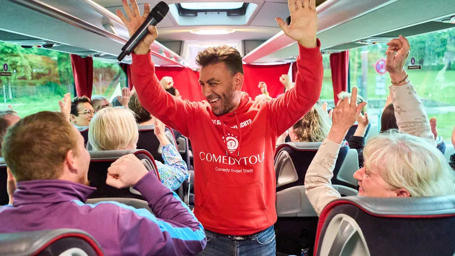 Man with microphone entertains bus passengers.