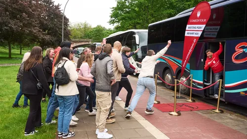 People entering a bus with a comedy tour banner.