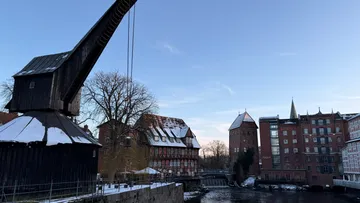Historischer Kran und Gebäude an einem Fluss.