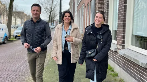 Three people walking on a city sidewalk.