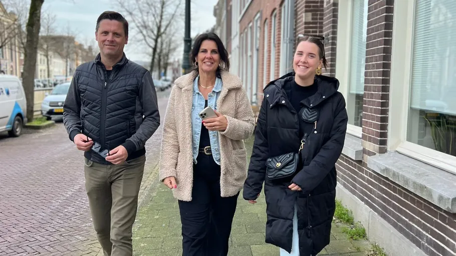 Three people walking on a city sidewalk.