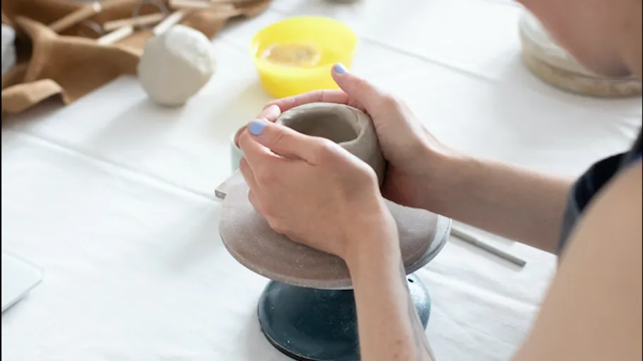 Hände formen Tontopf auf Töpferscheibe.