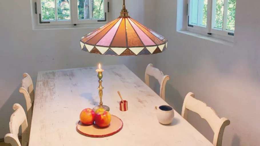 Dining table with lamp, apples, and candle.