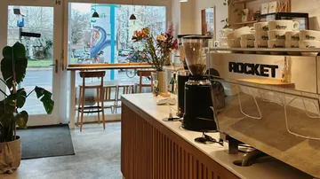 Café-Innenraum mit Espressomaschine und Sitzgelegenheiten.