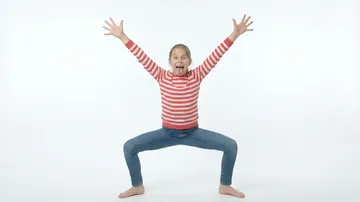 Child in striped shirt poses excitedly on white background.