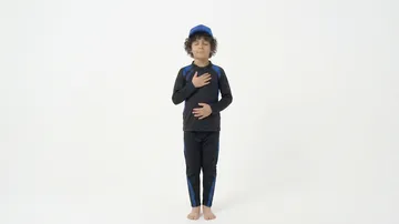 Child meditating with eyes closed indoors.