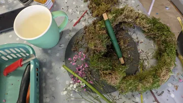 Kränzebasteln mit Moos auf Tisch.