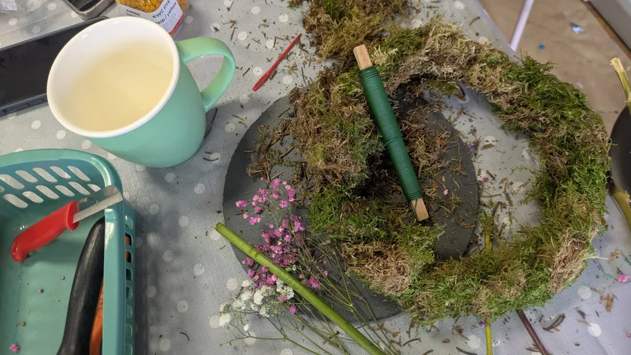 Wreath making with moss on table.