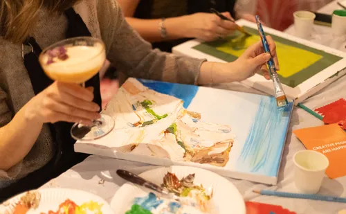 Person painting with drink in studio setting.