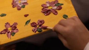 Hand painting flower on yellow surface.