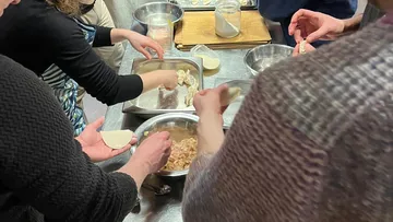 Leute machen Dumplings in einer Küche.