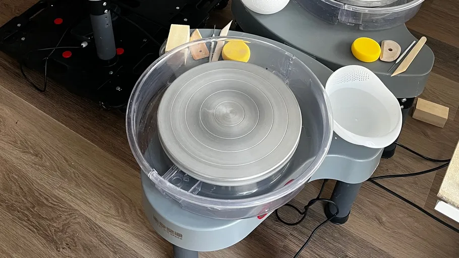Pottery wheel with tools on wooden floor.