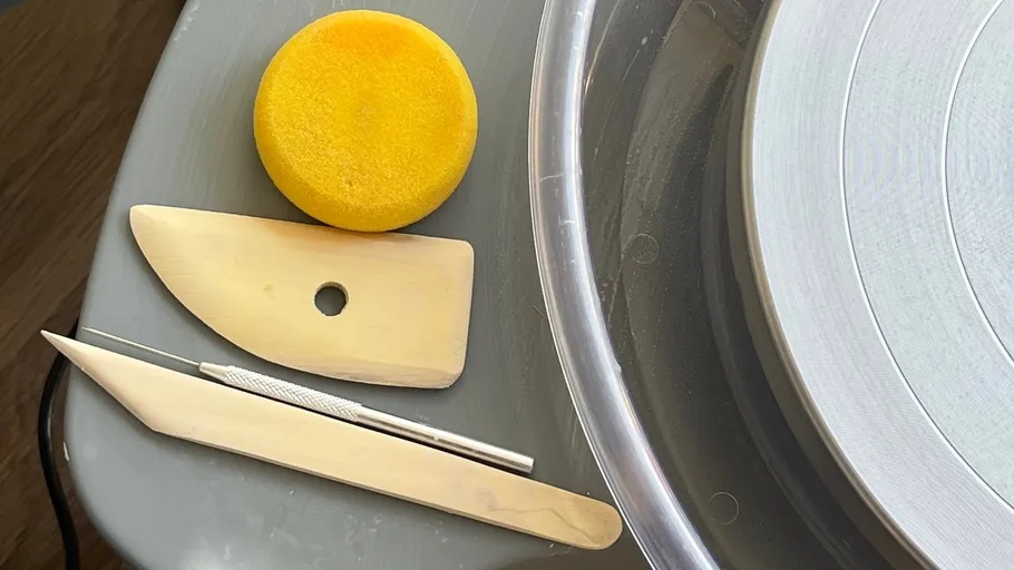 Pottery tools on a table beside wheel.