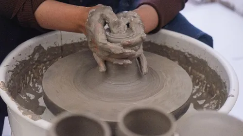 Hands shaping clay on a pottery wheel.