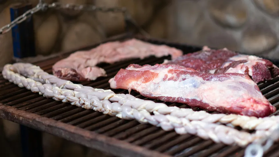 Raw sausages and meat on a grill.