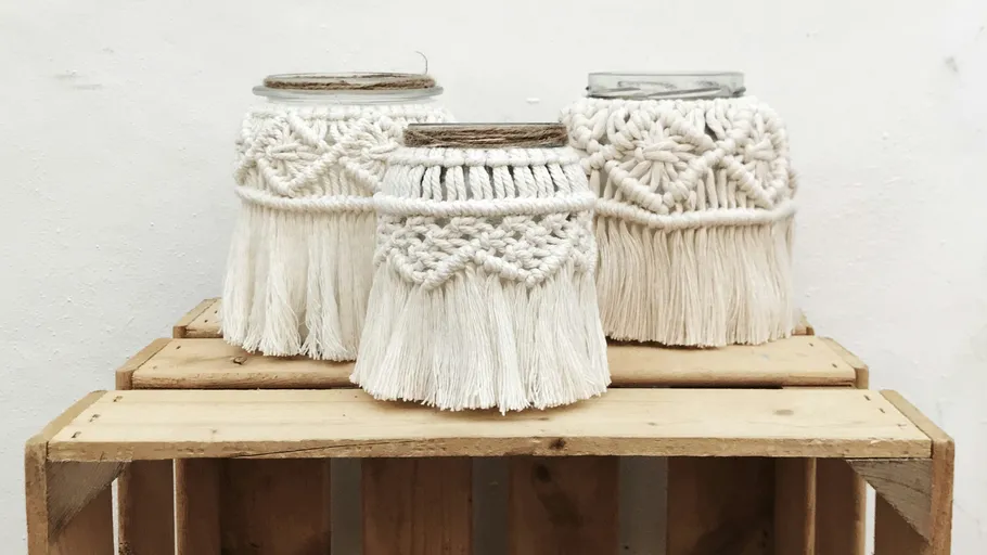 Macrame-decorated jars on wooden crate.