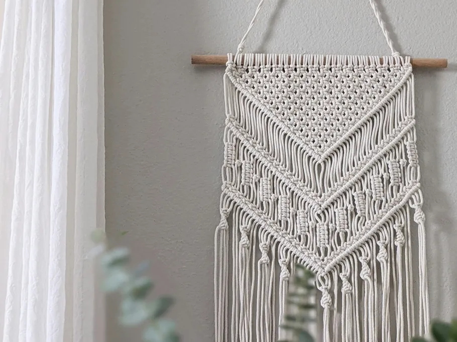 Macramé wall hanging on gray wall.