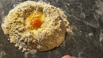 Flour mound with an egg on a countertop.