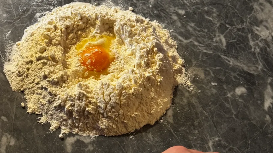 Mehlhügel mit einem Ei auf einer Arbeitsplatte.