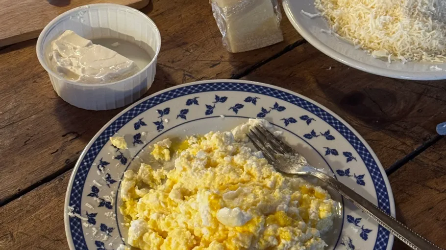 Teller mit Rührei und Käse, Holztisch.