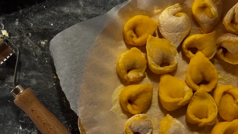 Homemade tortellini on parchment paper with cutter.