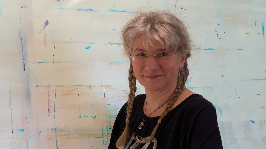 Smiling woman with braids in front of abstract art.