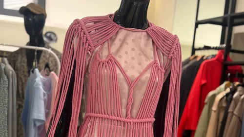Pink rope dress on mannequin in clothing store.