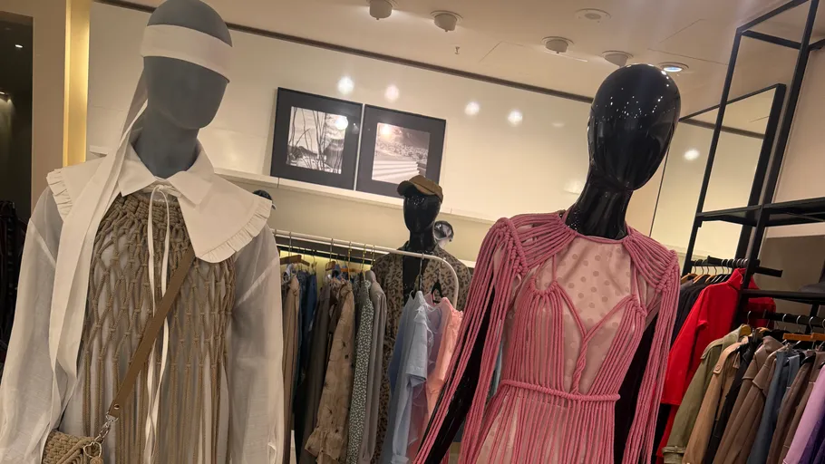 Mannequins wearing knitted dresses in clothing store.