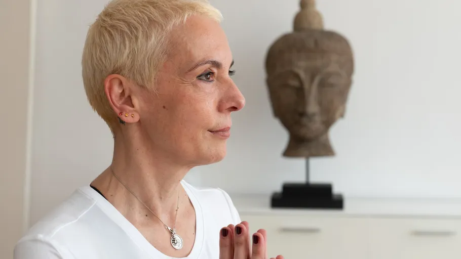 Person meditating in front of Buddha statue.