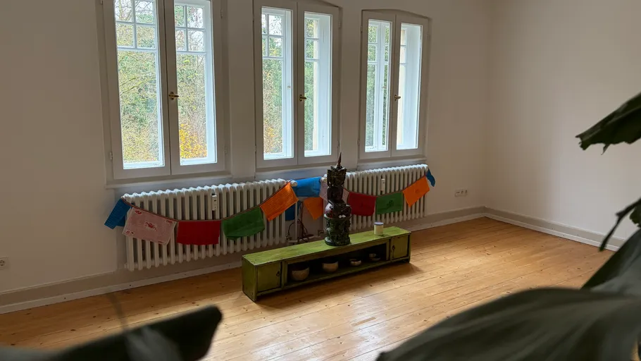 Room with colorful flags and statue by windows.