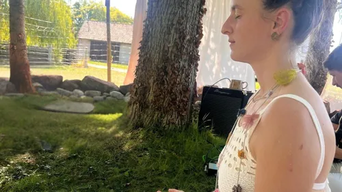 Woman meditating outdoors near trees.