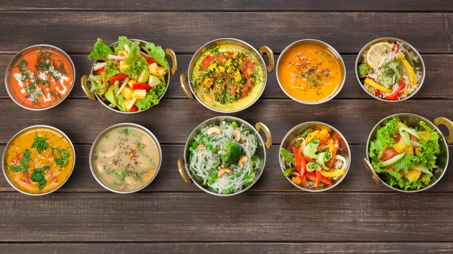 Various Indian dishes arranged on wooden table.