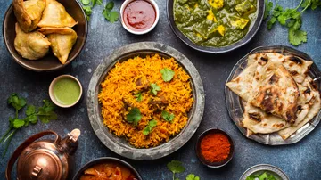 Indian dishes with rice, bread, curry, and samosas.