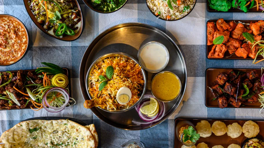 Assorted Indian dishes on checkered tablecloth.