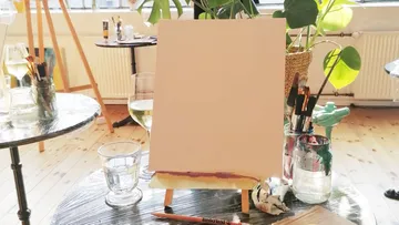 Canvas on easel with art supplies nearby.