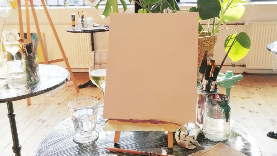 Leinwand auf Staffelei mit Kunstbedarf in der Nähe.