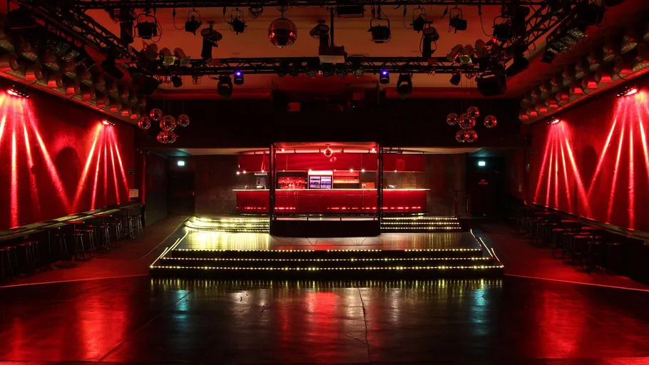 Leerer Nachtclub mit roter Beleuchtung und Bühne.