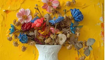 Bunte Blumen in weißer Vase vor gelbem Hintergrund.