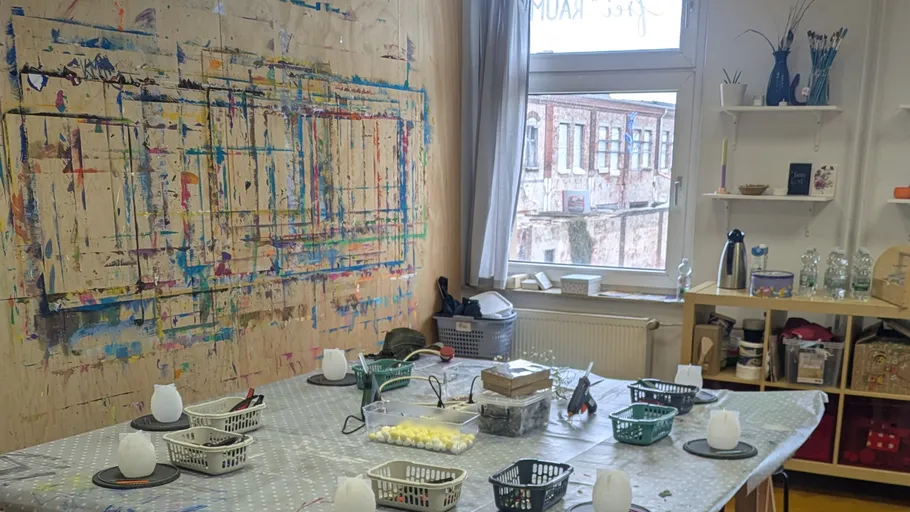 Art studio with colorful painted wall, supplies on table.