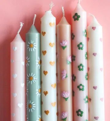 Decorative candles with floral patterns on pink background.