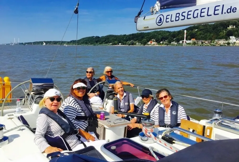 Group of women on a sailboat, river background.