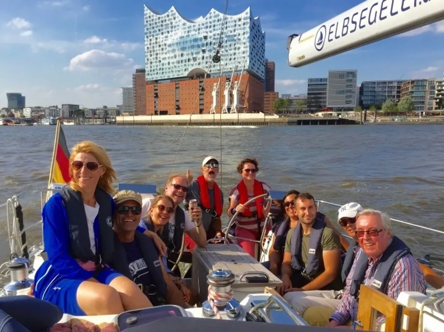 Group on a sailboat near a modern building.