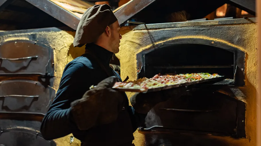 Bäcker legt Pizza in traditionellen Ofen.