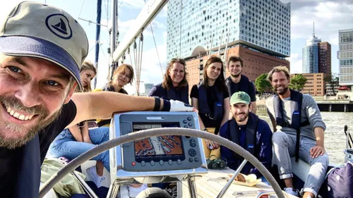 Gruppe von Menschen lächelt auf Segelboot im Hafen.