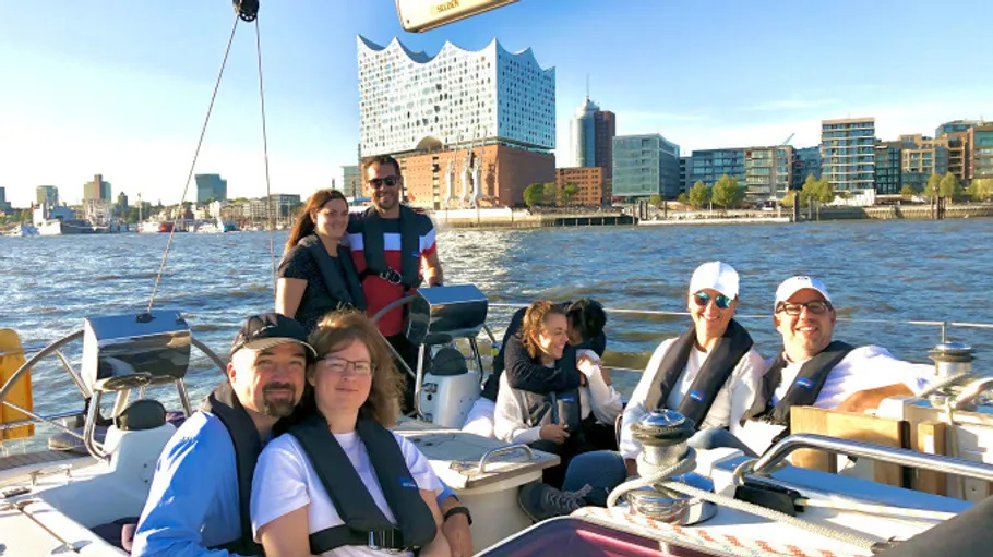 Group on sailboat with city skyline backdrop.