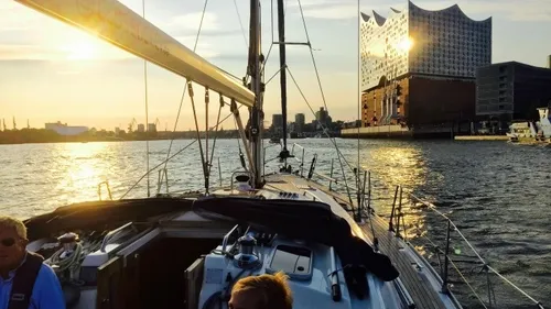Segelboot nähert sich Hafen in Sonnenuntergang.