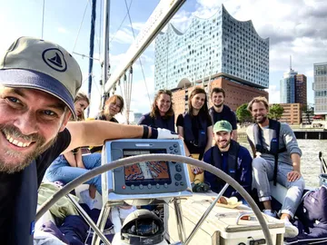 Group sailing near modern concert hall.