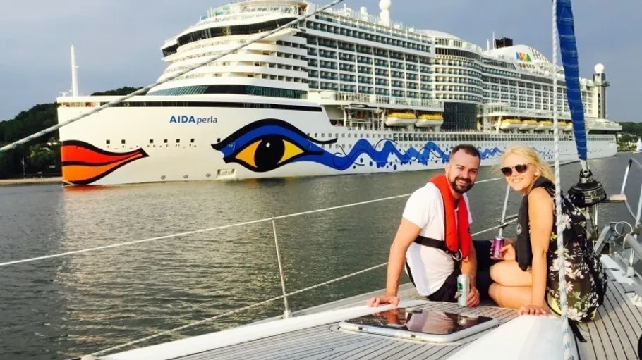 Couple sitting on boat near large cruise ship.