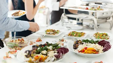 Buffet mit verschiedenen Salaten auf weißem Tisch.